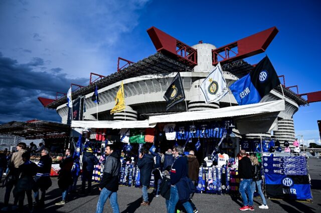 Supporters walk past Inter Milan' scarves, football jerseys and goodies on sale, outside t