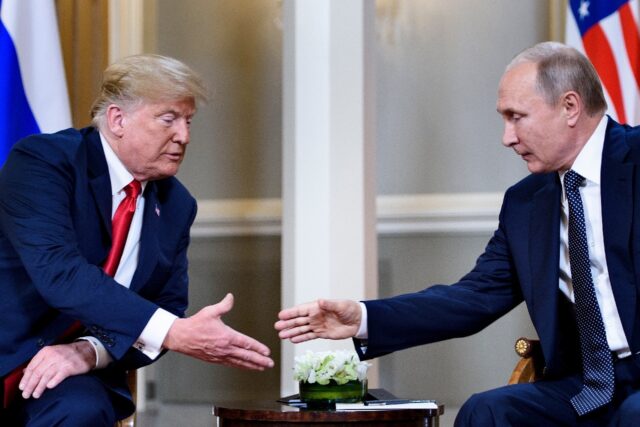 Then US president Donald Trump and Russian President Vladimir Putin reach to shake hands b