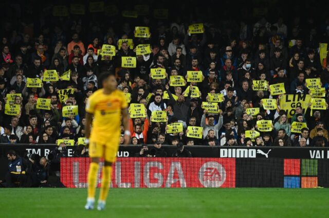 Valencia supporters hold placards from the stands reading "Lim go home"