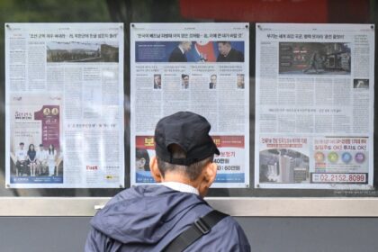 A man walks past a newspaper displayed on a street in Seoul with coverage on North Korea's