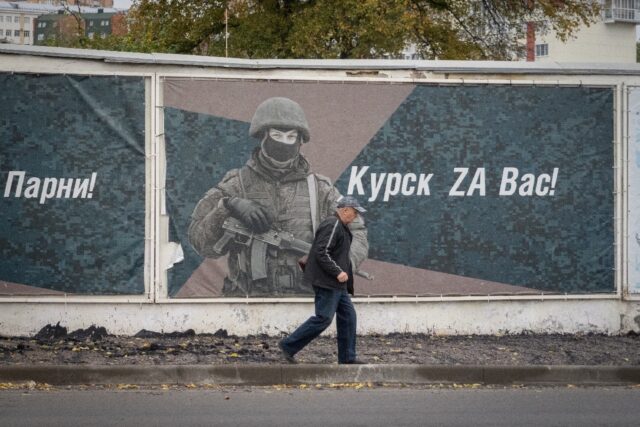 A man walks past a wall adorned with banners honouring Russian servicemen participating in