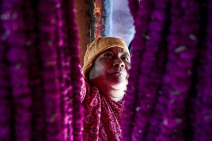 A woman arranges garlands made of globe amaranth in Nepal's Gundu village, where the flowe