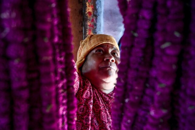 A woman arranges garlands made of globe amaranth in Nepal's Gundu village, where the flowe