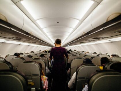 A woman is standing inside an airplane.