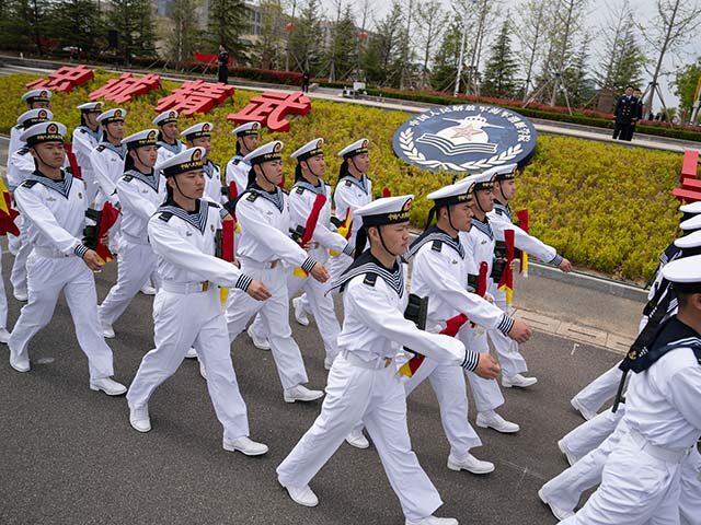 Sailors march past the insignia for the People's Liberation Army (PLA)'s naval submarine a