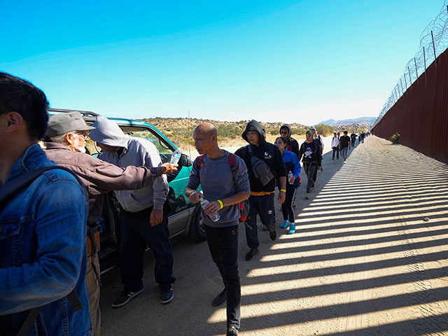 Sam Schultz, second from left, hands out water bottles to a line of asylum-seeking migrant