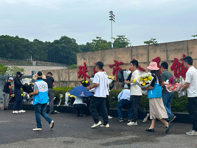 Volunteers relocate flowers laid outside the "Zhuhai People's Fitness Plaza" to a barrier