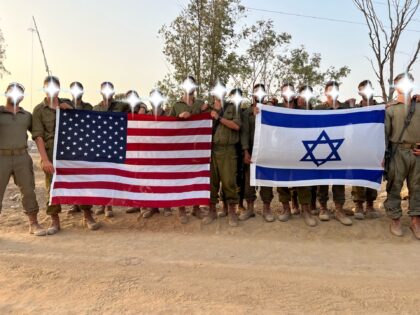 Israeli soldiers hold U.S. and Israeli flags at a staging area outside Gaza prior to the g