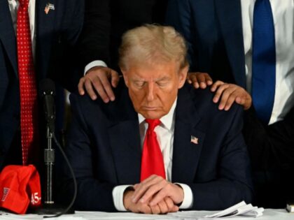 Former US President and Republican presidential candidate Donald Trump prays during a roun