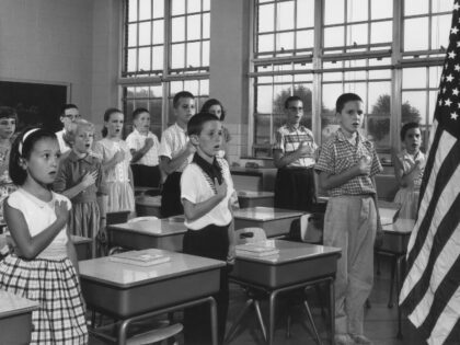 circa 1960: School children holding their hands over their hearts while reciting the Pledg