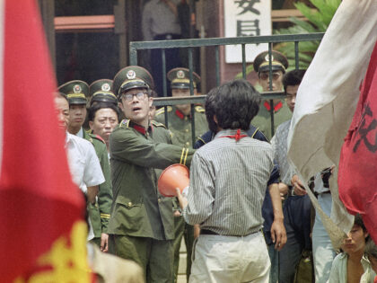 A policeman tries to disperse demonstrating students from the entrance of police headquart