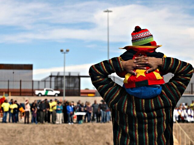 A migrant man carries his son on his shoulders during a binational mass in memory of the m