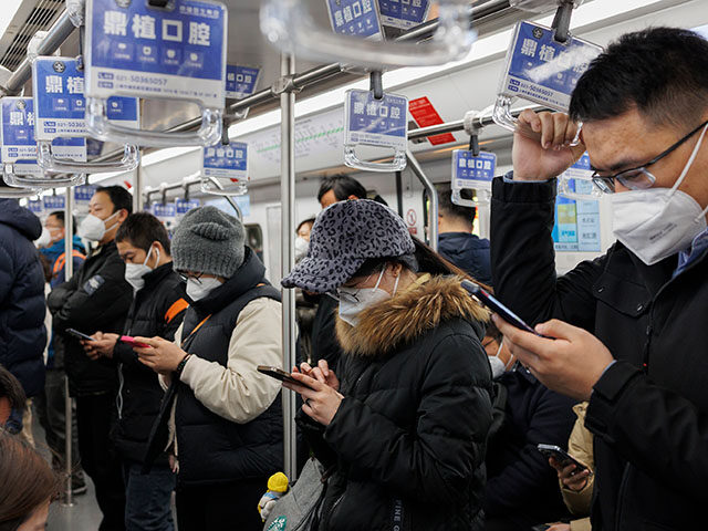 People with protective masks look at their smartphones in a subway car on January 04, 2023