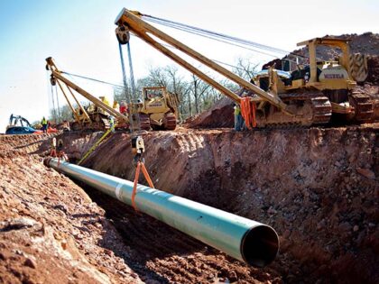 A sixty-foot section of pipe is lowered into a trench during construction of the Gulf Coas