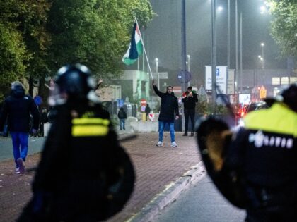 A supporter waves a Palestinian flag in front of Police officers from Mobile Unit (ME) dur