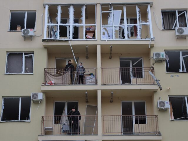 Local residents stand on the balconies of their damaged apartments following a drone attac