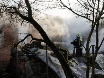 A rescuer works to extinguish a fire in a house following a drone attack in the village of