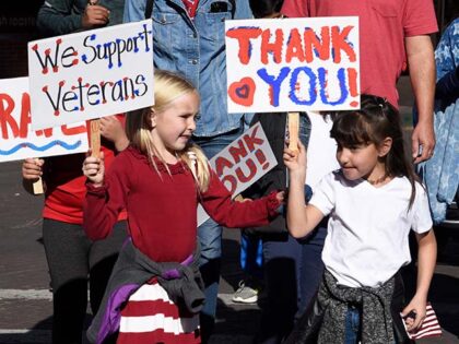 Children walking in a Veterans Day parade in Santa Fe, New Mexico, hold signs expressing t