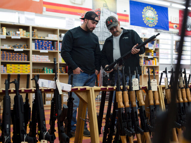 Customers look at a long gun at a gun shop on November 5, 2016, in Merrimack, New Hampshir