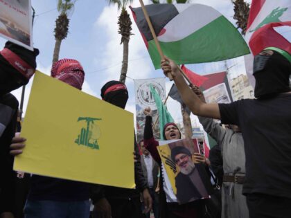 Palestinian activists chant slogans as they hold posters with pictures of late Hezbollah l