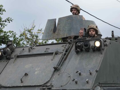 A Lebanese army soldier on an APC (Armored Personnel Carrier) flashes victory sign, as a c