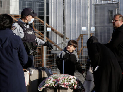 A Canadian police officer speaks with a migrant family from Afghanistan who walked across