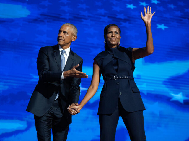 Former President Barack Obama and former first lady Michelle Obama appear on stage in betw