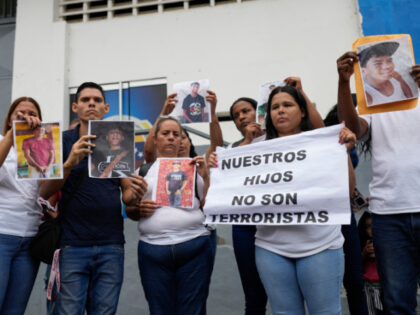 The relatives of detained young men hold pictures of them and a sign that reads in Spanish