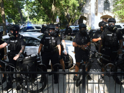 Orlando Police wear gas masks after they arrested two people during a protest march to com