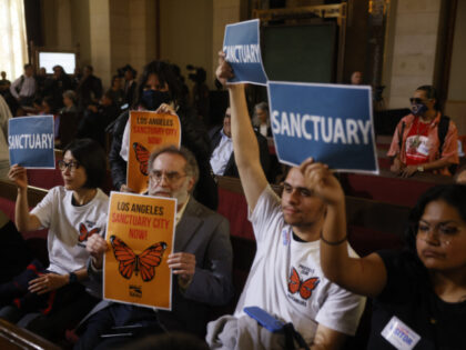 People in the audience hold up signs in support of immigrants as the Los Angeles City Coun