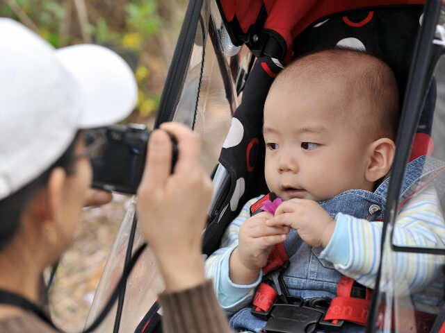 A South Korean woman takes a photo of her baby sitting on a pushchair during their family