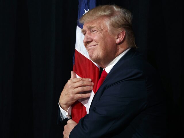 Republican presidential candidate Donald Trump hugs an American flag as he arrives to spea