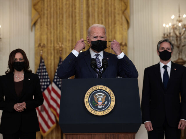 U.S. President Joe Biden (C) removes his mask before delivering remarks on the U.S. milita