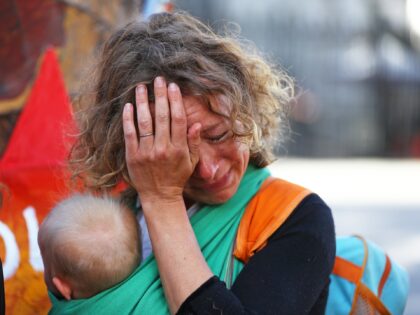 A mother cries while she holds her baby during a protest organised by Mothers Rise Up at D