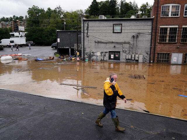 FILE - A man walks near a flooded area near the Swannanoa river, effects from Hurricane He