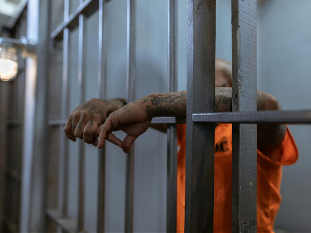 tattooed man in orange jumpsuit arrested in prison, jail cell