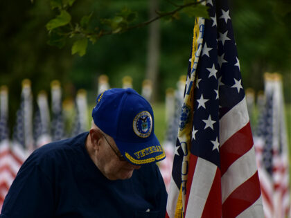 An Elderly veteran Standing Beside an American Flag