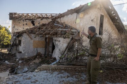 An Israeli soldier points at a house hit by Hezbollah rockets in the deserted northern Isr