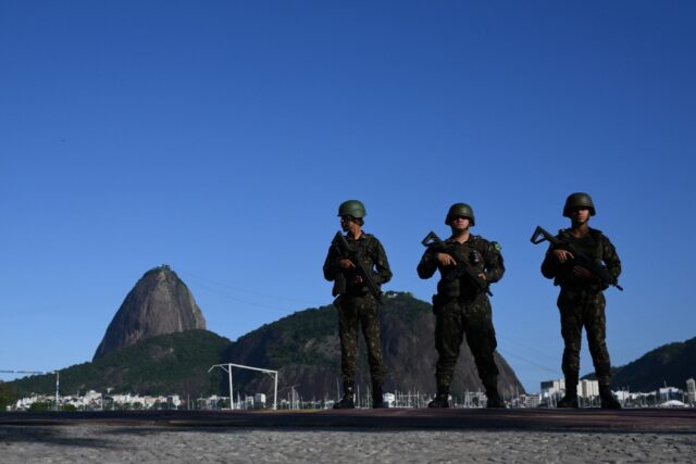 Brazilian army soldiers stand guard on Botafogo beach with the Sugar Loaf mountain in the