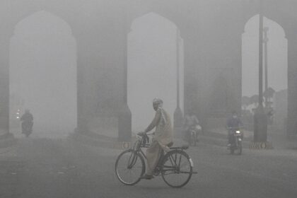 A cyclist rides along a street engulfed in thick smog in Lahore in early November