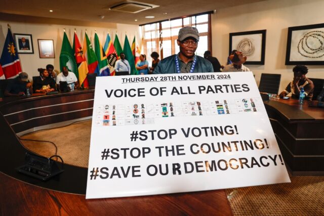A member of the Namibian opposition displays a banner calling for a halt to the voting pro