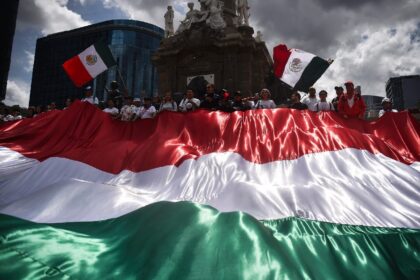 Opponents of Mexico's judicial reforms hold a giant flag during a protest in Mexico City