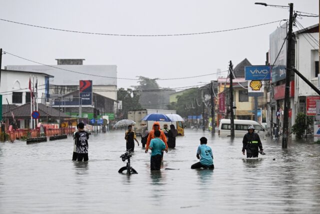 People wade through a flooded street during heavy rain in Pasir Puteh in Malaysia's Kelant