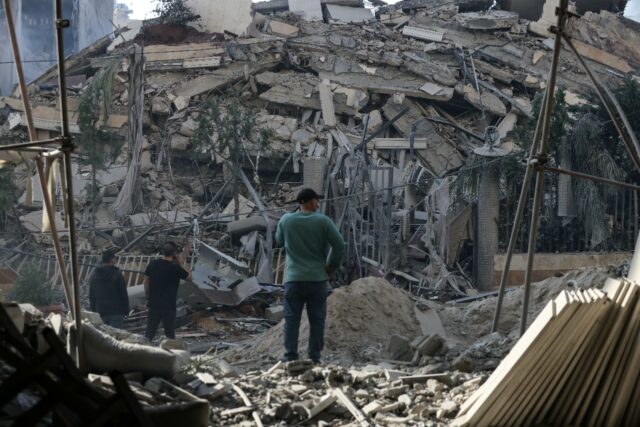 Residents stand in front of a levelled building following an Israeli airstrike that target