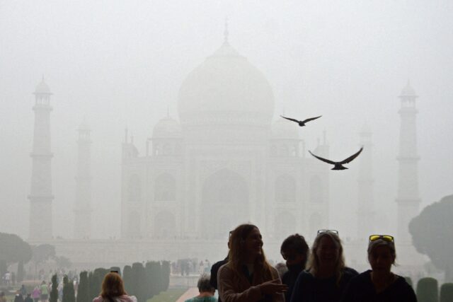 Tourists visit the Taj Mahal on a cold smoggy morning in Agra on November 18