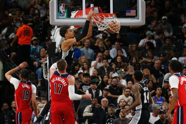 Victor Wembanyama of the San Antonio Spurs dunks past Jonas Valanciunas of the Washington