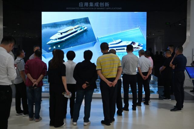 Visitors look at a video about battery-powered ships in the showroom at the headquarters o