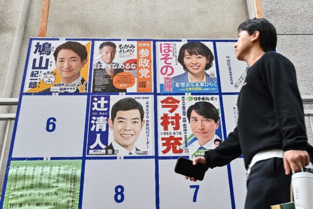 A man walks past a billboard displaying campaign posters for the country's recent general