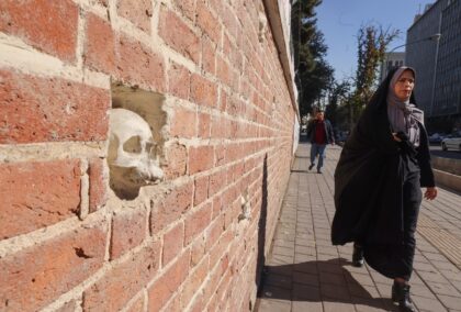 A woman walks past the former US embassy compound in Tehran, which has skulls embedded in