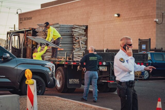 Workers unload fencing from a truck at the Maricopa County Election and Tabulation Center